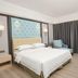 Master Hotel Huizhou guest room with king bed, blue accent chair, and floor-to-ceiling curtains