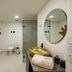 First Class Hotel Medellín bathroom with walk-in shower, wall-mounted toilet and round mirror