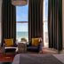 West Rocks Townhouse Eastbourne guest room with sea view, two chairs by tall windows and curtains