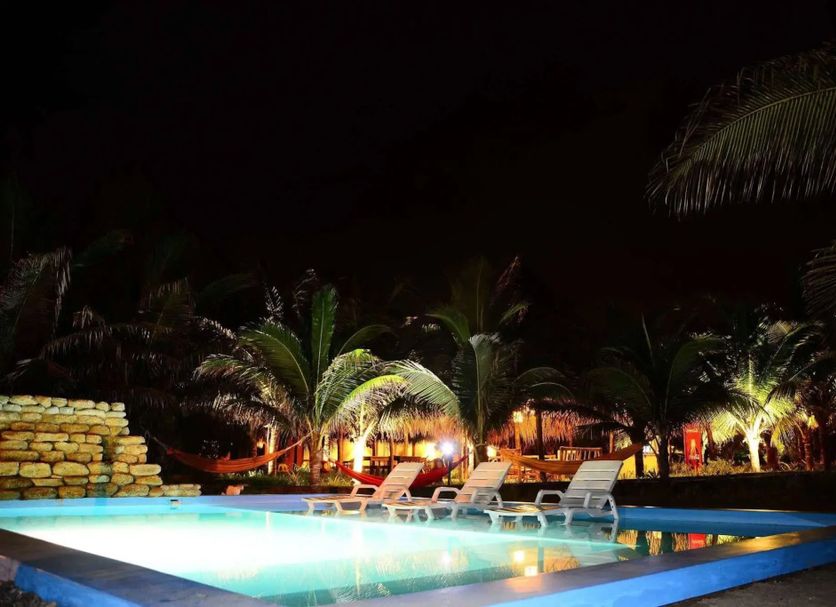 La Casa de Sebas, Máncora: illuminated outdoor pool with lounge chairs and palm trees at night