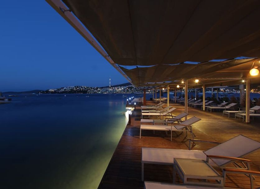 Olira Boutique Hotel&spa in Bodrum with a waterfront deck, lounge chairs, and calm sea at dusk