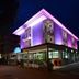 Hotel Concorde in Cesenatico, lit purple at night with a corner facade and ground-floor terrace