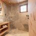 Hotel Leitenhof 4 Sterne Superior bathroom with walk-in shower, wood vanity and window in Scheffau am Wilden Kaiser