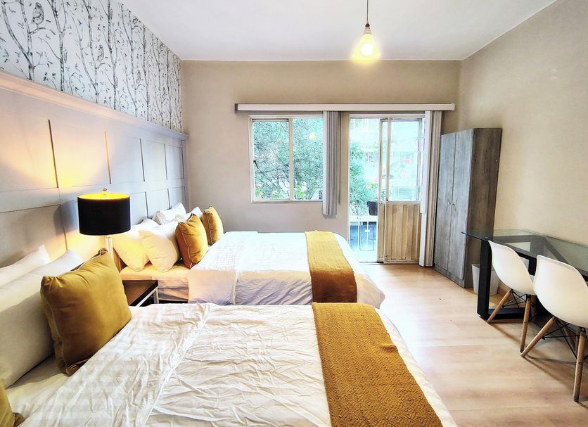 Casa Panuco in Mexico City guest room with two beds, balcony view, desk and modern seating