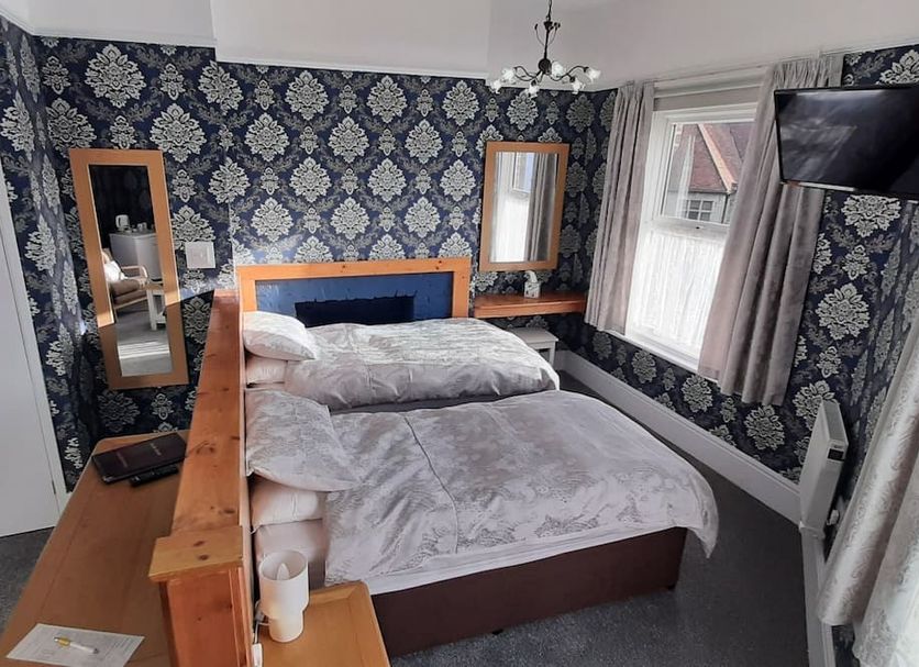 Brooke House in Shanklin: double bed, patterned wallpaper, wall-mounted TV, and window with curtains