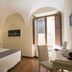 B&B Quattro Cantoni in Siena guest room with arched ceiling, bed, desk and open window