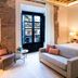 Sofraga Palacio in Ávila guest room with sofa bed, exposed brick walls, and balcony doors