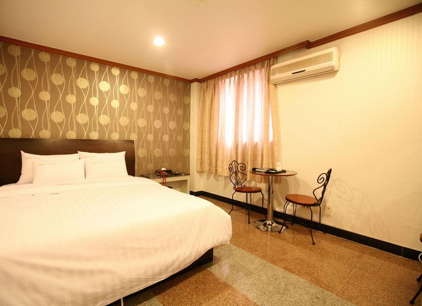 New World Hotel Yongsan room in Seoul with a double bed, desk, chairs, window and wall-mounted AC.