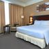 Hotel Menara Bahtera Balikpapan guest room with king bed, armchair, bedside lamps, and curtain-draped window