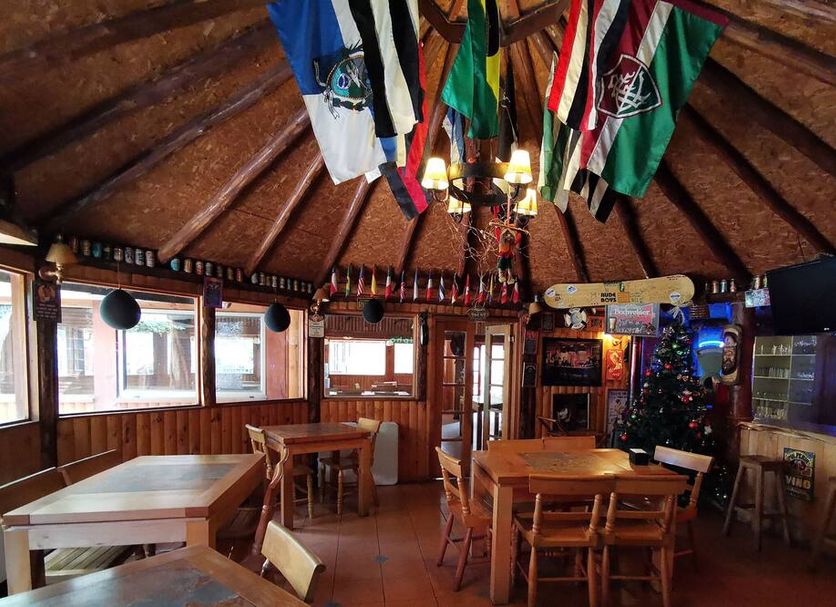 Cabañas Bordenieve in Termas de Chillan, rustic lodge dining room with wood walls and hanging flags