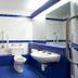 Travelodge Bedford Marston Moretaine bathroom with blue-and-white tiles, bathtub, toilet, sink, and mirror.