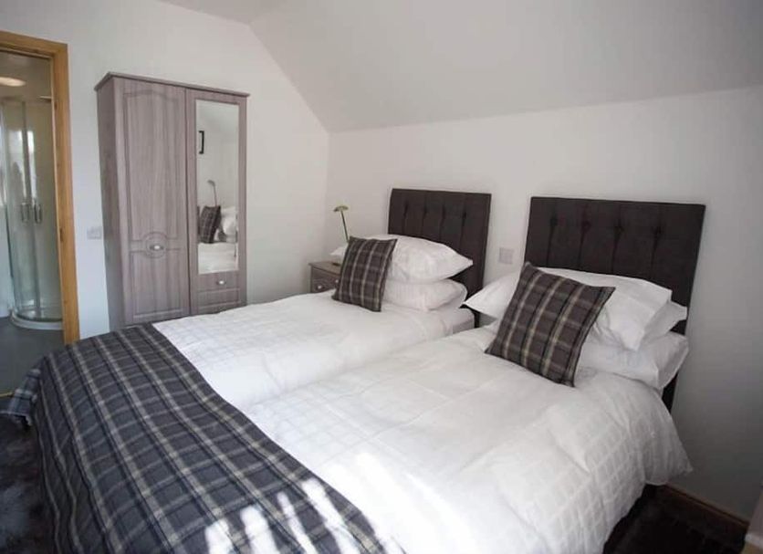 By The Bay, Peterhead: twin beds with plaid throws and wardrobe in a compact guest room