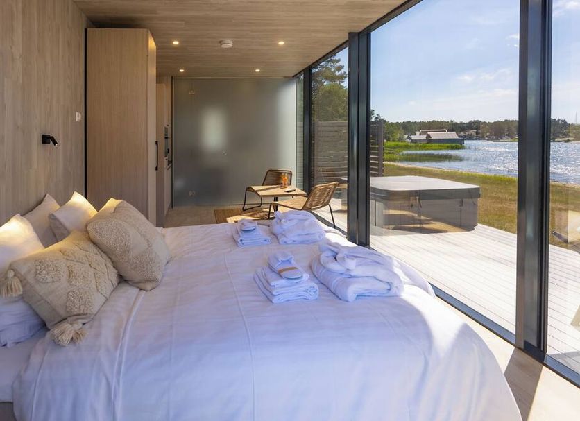 Käringsund Resort in Eckerö guest room with bed beside floor-to-ceiling windows and lake view