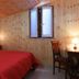 Albergo Umbria in Città di Castello bedroom with red bedspread, wood-paneled walls, and window