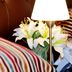 Oporto Hotel Boutique in Santiago: striped pillows, bedside lamp, white lilies and phone on a bed