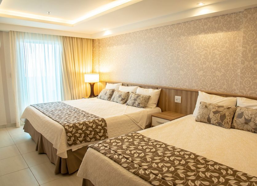 Paradiso Macae Hotel in Macaé guest room with two double beds, bedside lamp, and sheer curtains