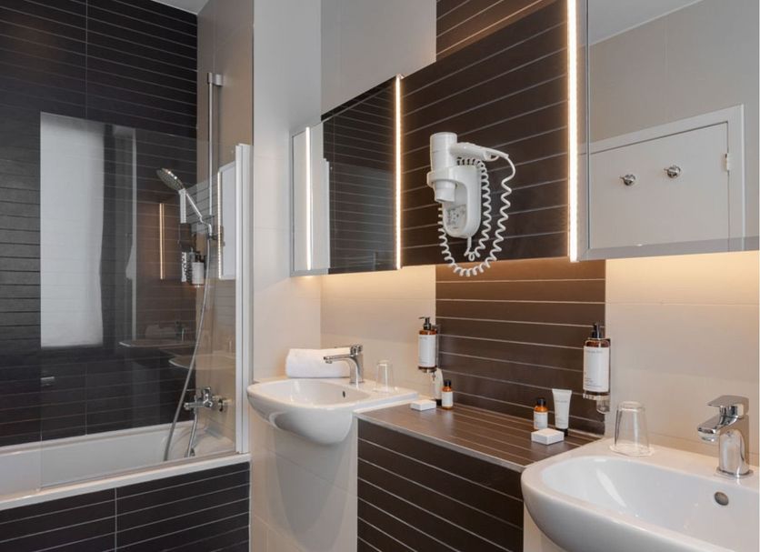 Craves Hotel Brussels bathroom with bathtub, shower, double sinks and wall-mounted hair dryer