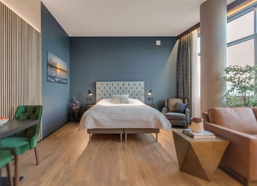Hótel Múli Reykjavik guest room with bed, seating area, large windows and blue accent wall
