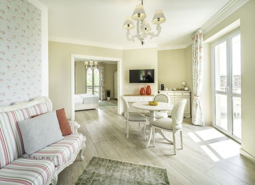 Locanda Borgo Vecchio in Neive: bright sitting room with striped sofa, dining table and balcony doors