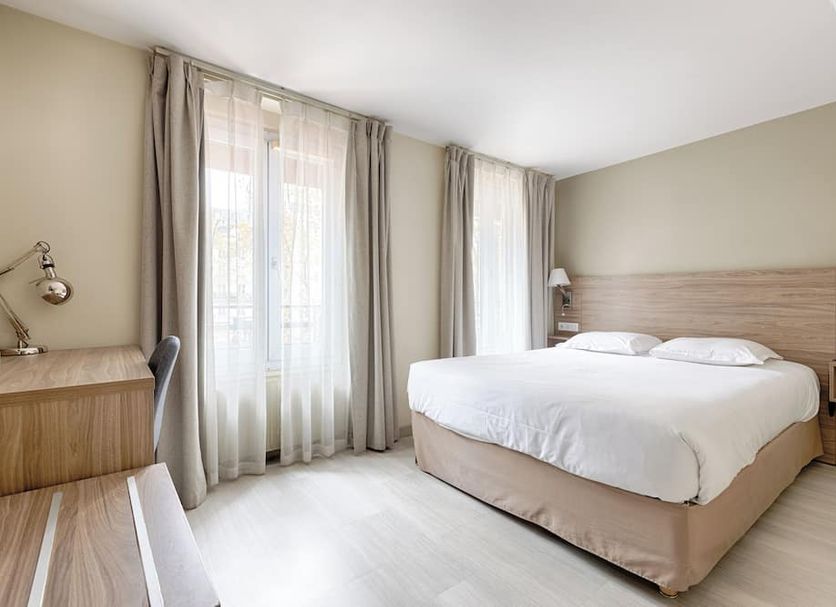 Hotel Marmotel Etoile in Paris bedroom with queen bed, sheer curtains, and bedside tables