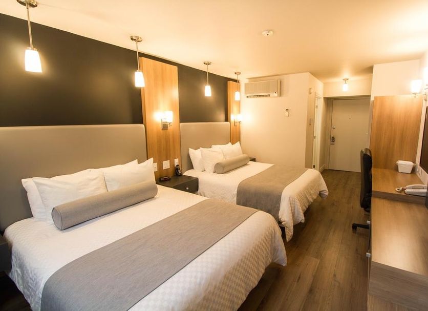 Hotel Marineau Shawinigan guest room with two beds, desk, and warm wood accents in Shawinigan
