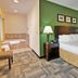 Holiday Inn Express & Suites Pekin (Peoria Area) By IHG guest room with king bed and adjacent tiled soaking tub