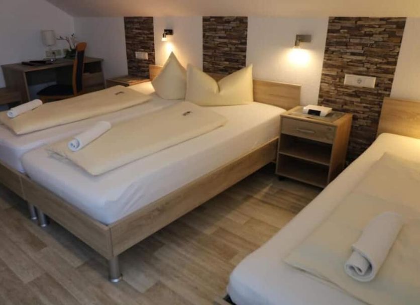 Hotel-Gasthof Zur Rose in Weißenhorn guest room with three beds, desk, and wall lights