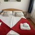 Rudi Hiti's Guest House in Bled bedroom with double bed, red bed runners, and folded towels