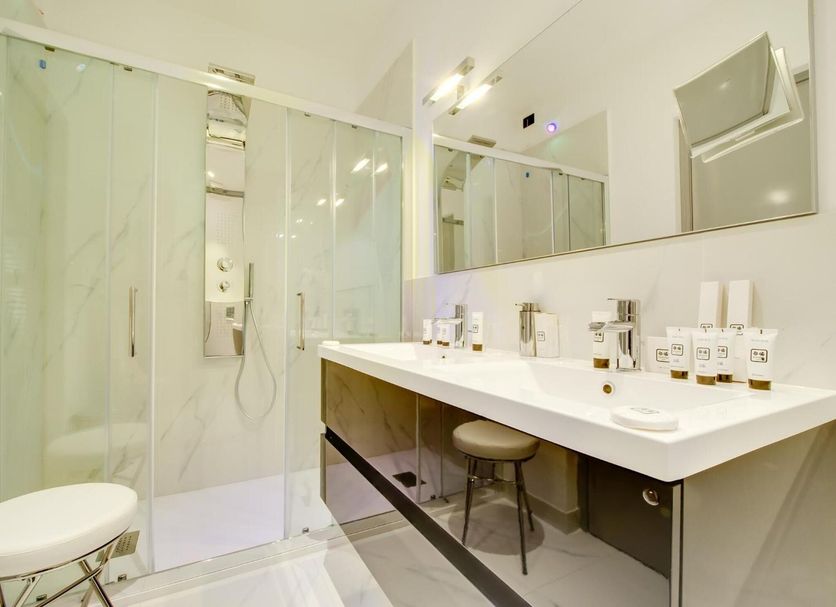 Queen Palace Suites Rome bathroom with glass shower, double vanity and modern mirrors