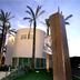 Palazzo Giordano Bruno in Nola, modern hotel exterior with palm trees and sculptural entrance at dusk