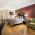 Red Roof Inn & Suites Knoxville East guest room with bed, desk, sofa and hardwood floor
