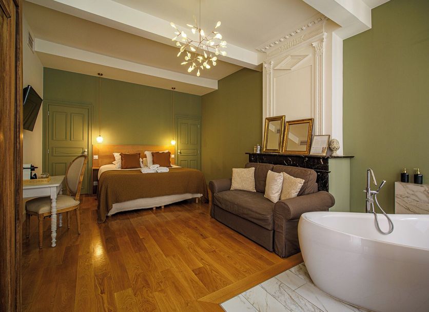 Maison d'Hotes Delga in Gaillac: guest room with bed, sofa, desk and freestanding bathtub