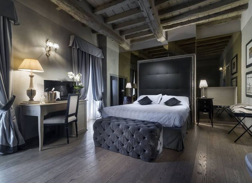Villa Casagrande Resort E Spa room with upholstered bed, desk, and wood-beamed ceiling in Figline Valdarno