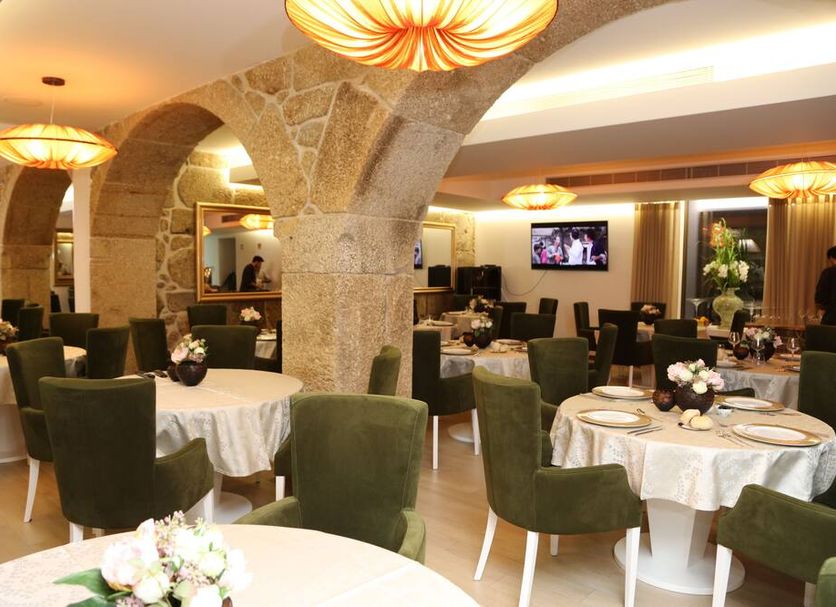 Hotel Rural Quinta Das Quintães in Penafiel: stone-arched restaurant with round tables and green chairs