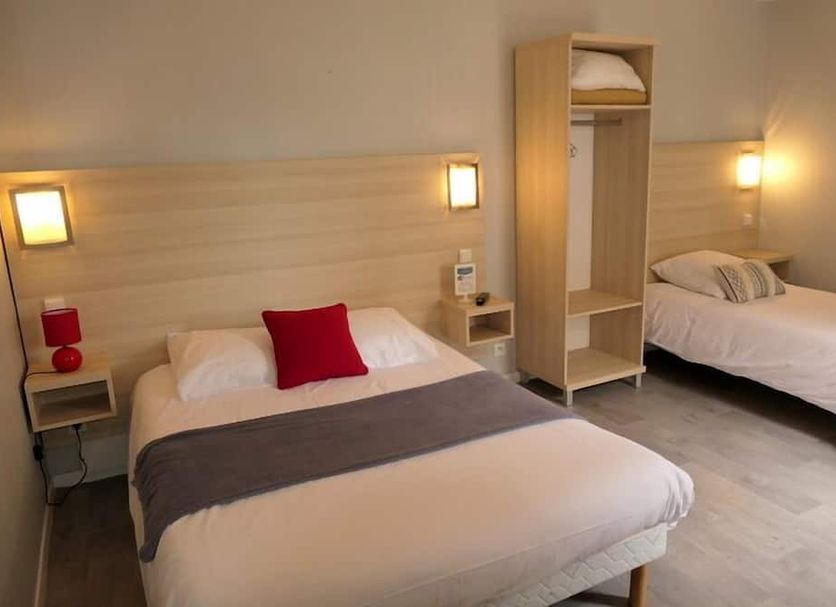 Hotel Le Canada in Hermanville-sur-Mer guest room with two single beds, wall lights and a wardrobe