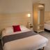 Hotel Le Canada in Hermanville-sur-Mer guest room with two single beds, wall lights and a wardrobe