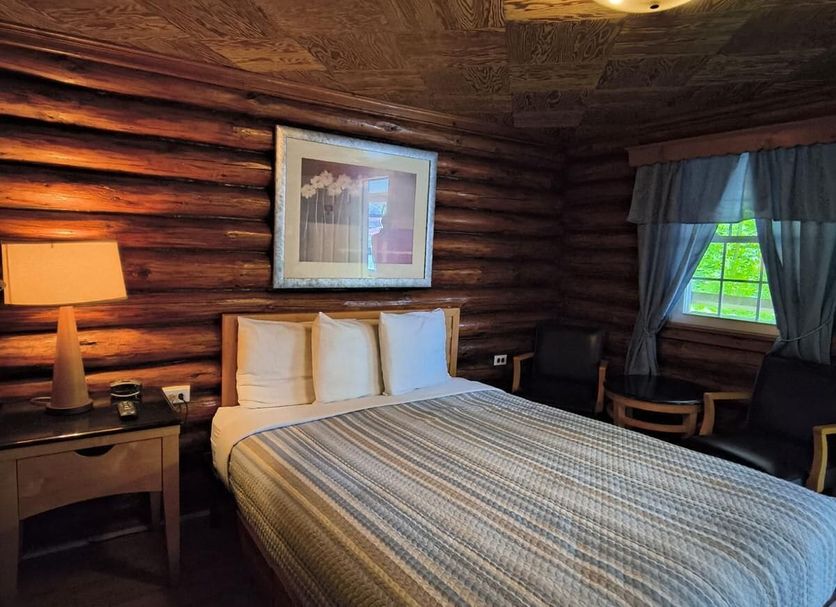 Seven Dwarfs Motel and Cabins in Lake George: rustic cabin-style guest room with queen bed, lamp, and window seating