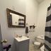 Bathroom at The Macaw Guesthouse in New York with vanity, toilet, shower curtain and striped rug
