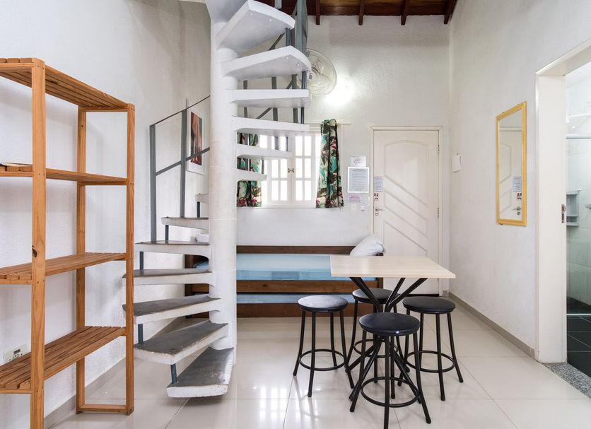 Recanto Maranduba, Ubatuba: loft-style room with spiral stairs, dining table, stools, and bathroom door