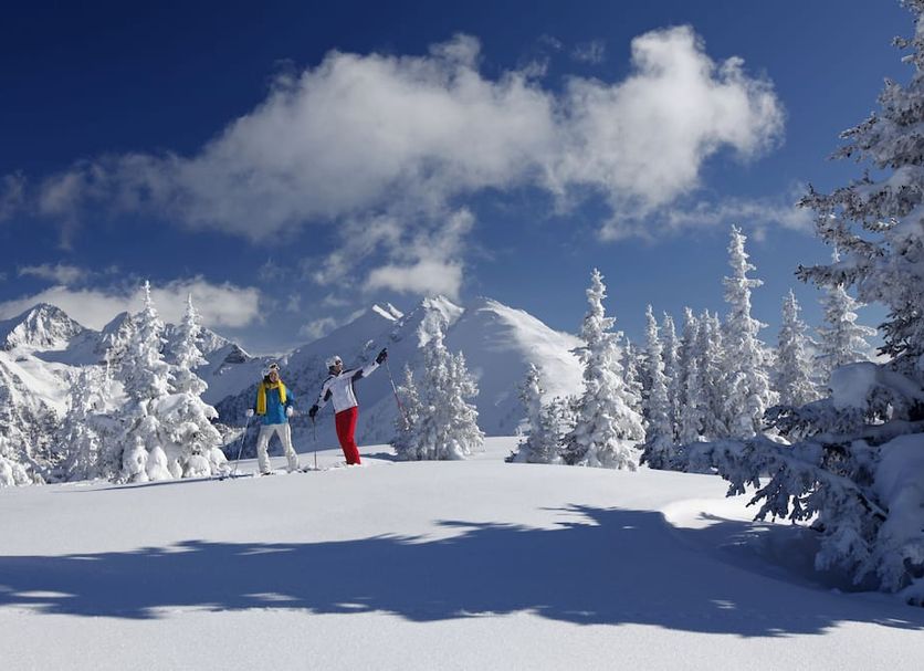 Sporthotel Royer in Schladming with skiers on a snowy alpine slope and frosted pine trees