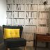 The Lawrence Burnley lounge chair with yellow cushion beside wooden side table and bookcase wallpaper
