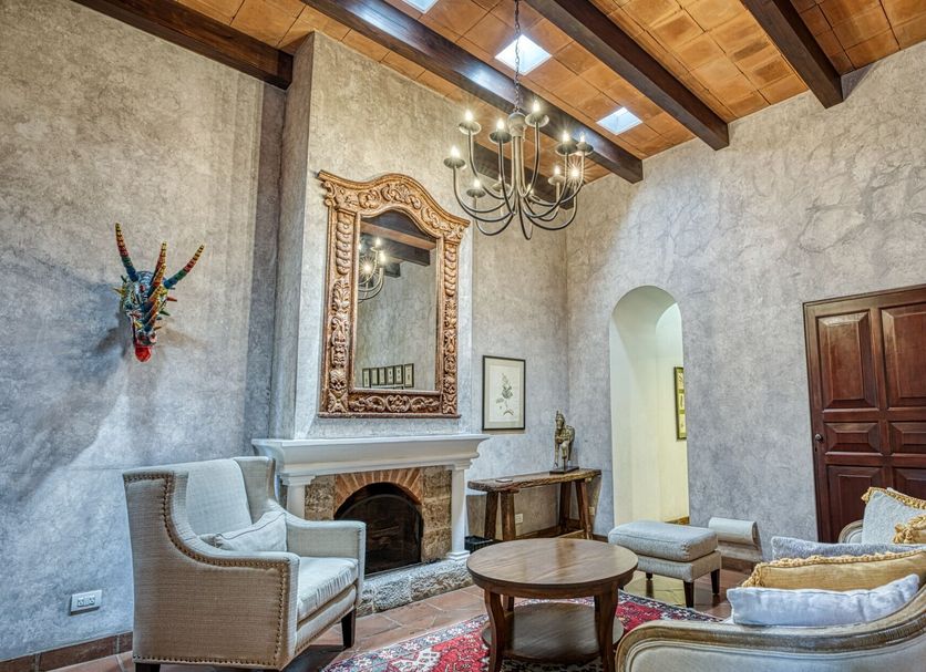 San Rafael Hotel in Antigua lounge with fireplace, chandelier, ornate mirror, and upholstered seating