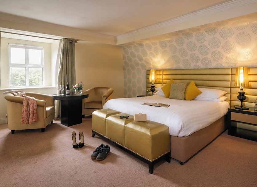 Castle Hotel Macroom guest room with king bed, seating area, window light and bedside lamps in Macroom