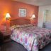 Best Budget Inn - Abilene guest room with bed, lamps, armchair and bathroom doorway
