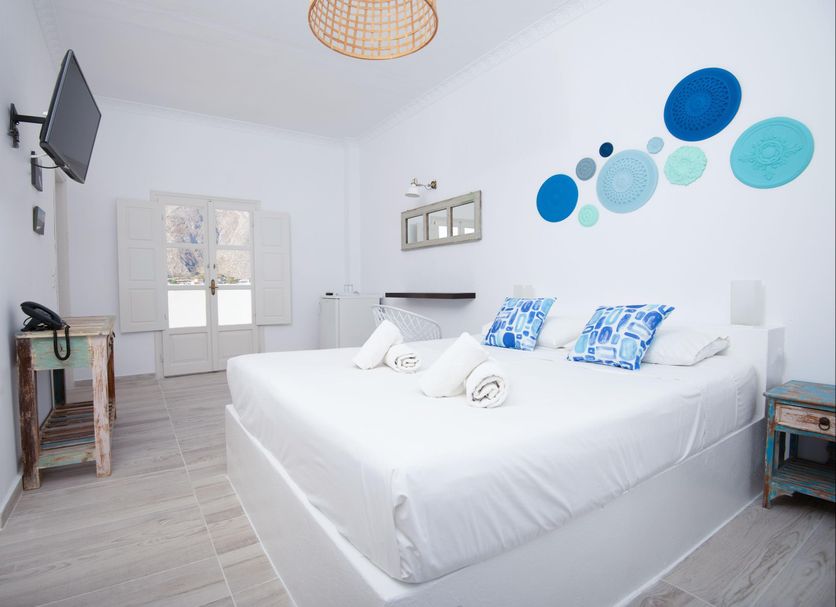 Villa Markezinis in Perissa: bright white guest room with double bed, wall-mounted TV, and blue wall art