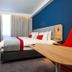 Holiday Inn Express Burton Upon Trent guest room with bed, desk, wall-mounted TV and blue accent wall