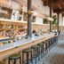 Wythe Hotel Brooklyn bar interior with long marble counter, stools, pendant lights and patterned tile floor