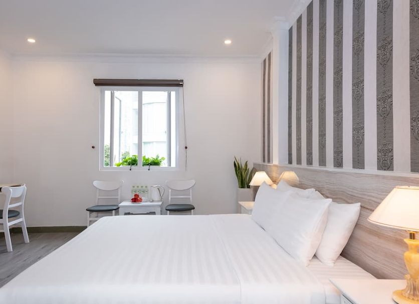 The One Hotel Ben Thanh in Ho Chi Minh City guest room with king bed, desk and window seating