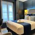 Hôtel Clairefontaine Paris guest room with double bed, navy accents, bedside lamps, and French windows
