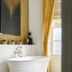 Townhouse on the Green Dublin bathroom with freestanding tub, marble fireplace, and tall window